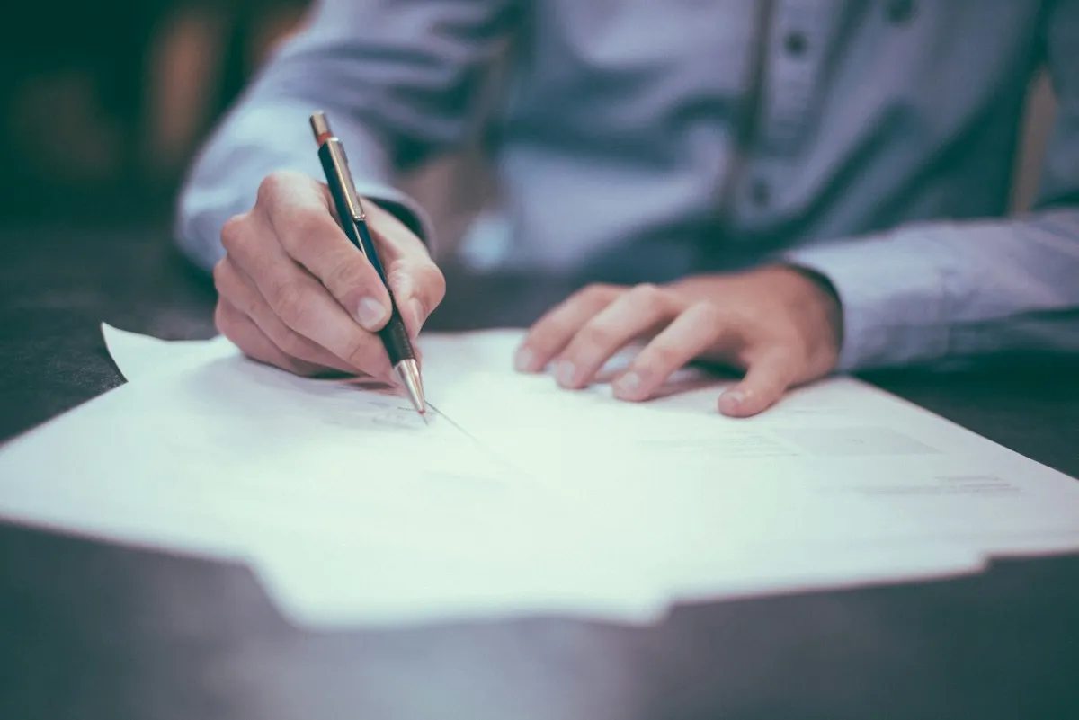 Applicant completing a paper form with a pen