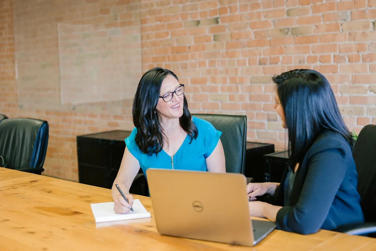 Two people discussing interview answers face to face at a desk